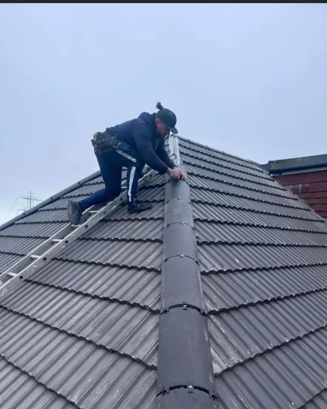 A Masters Roofing roofer bedding the ridge on a newly tiled hipped roof