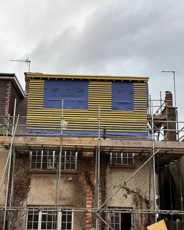 A dormer framed and sheeted at first floor, with the scaffold up and the roof stripped