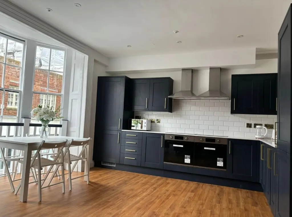 A finished shared kitchen in a converted property, with dark shaker units and integrated appliances