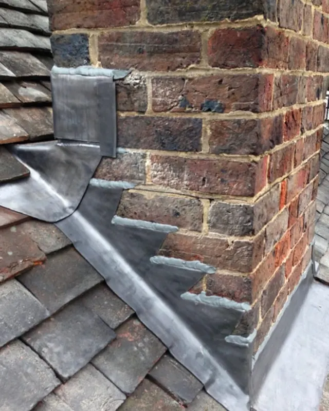 A new lead front apron and step flashing dressed into the brickwork of a chimney stack