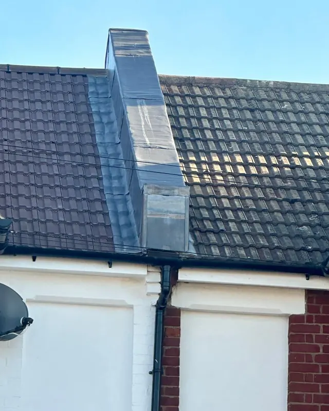 A dormer cheek clad in lead, with the roof tiling run up to the abutment