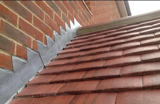 New lead step flashing raked into the brickwork above a run of clay plain tiles