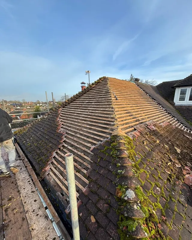 The same roof before work, with moss-covered tiles and a failed mortar ridge