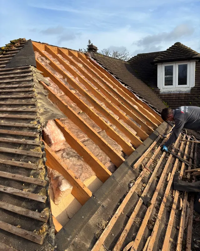 A roof stripped back to the rafters, with the old covering and battens removed