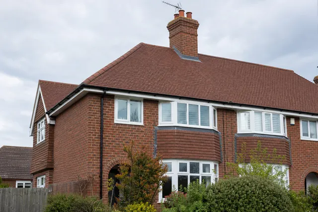 Completed full re-roof on a semi-detached house in Worthing, showing new plain tiling, dry ridge and new leadwork to the chimney