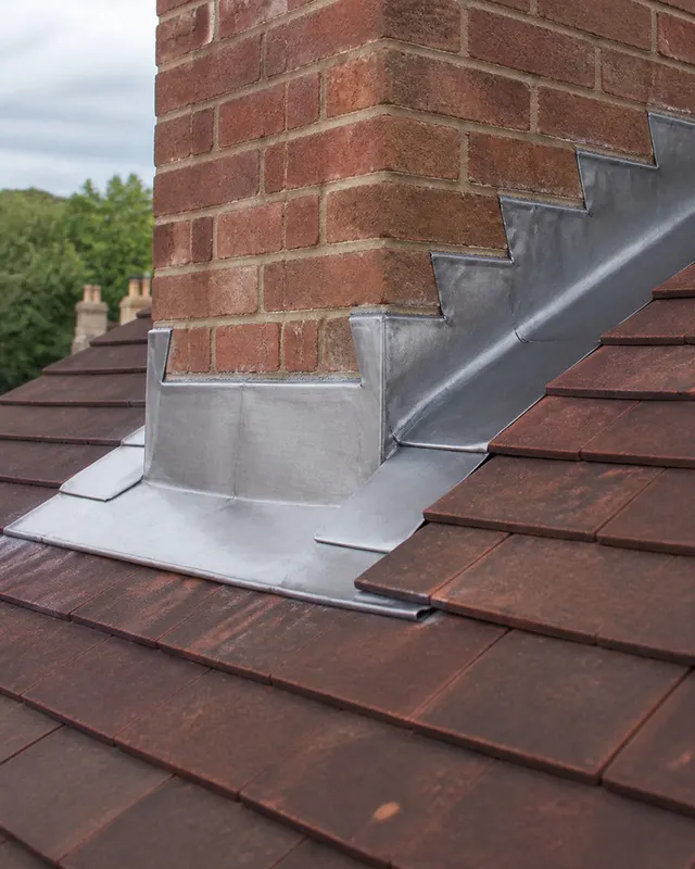 New lead step flashing and front apron dressed into the brickwork of a chimney stack in BN11