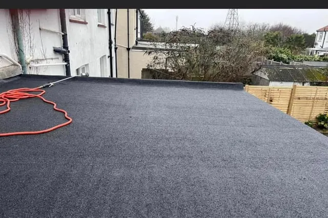 A repaired and re-covered flat roof deck finished in new felt, with the upstands and trim redressed