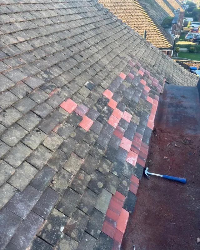 Replacement tiles bedded into a pitched roof alongside the original weathered tiling after storm damage
