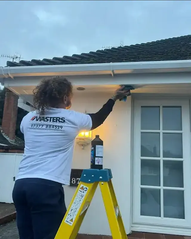 Dean Masters, owner of Masters Roofing & Construction, on site in branded workwear working on the soffit of a bungalow